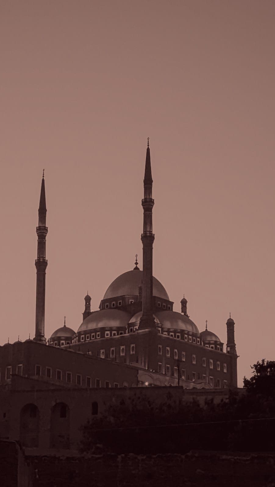 The Muhammad Ali Mosque at the Salah El-Din Citadel, Cairo, its domes and minarets lit against the sky at dusk.